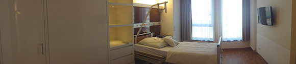 Schlafzimmer Dieses Bild zeigt das Schlafzimmer einer Familiensuite. In dem Zimmer befindet sich ein Bett und daneben ein Kleiderschrank. Der Raum hat zwei Fenster und an der Wand vor dem Bett hängt ein Fernseher.
