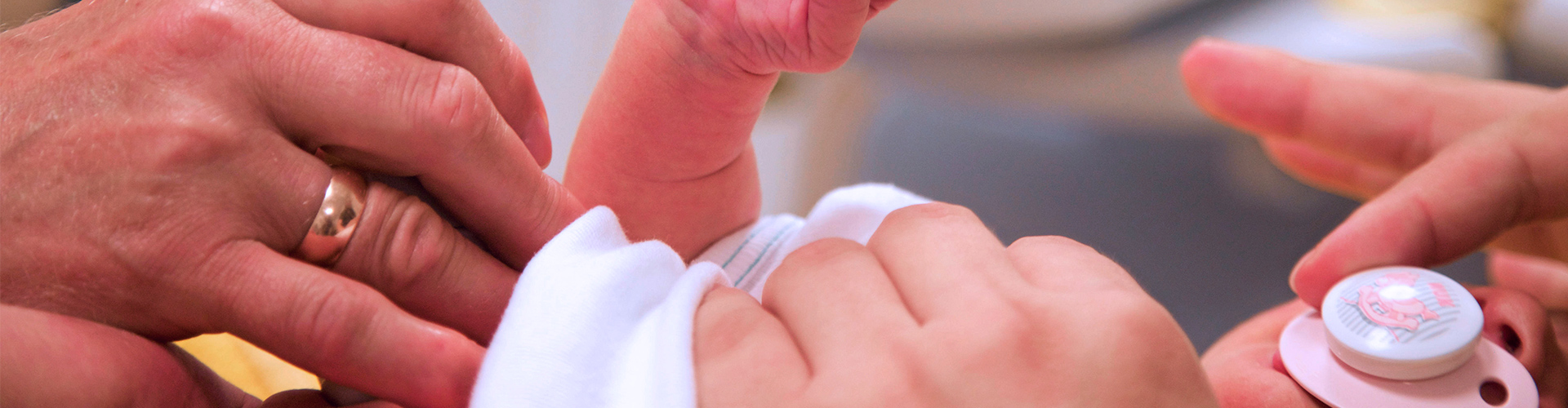 Dieses Bild zeigt ein Baby, das gerade von seinen Eltern gepflegt wird.